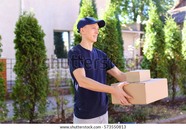 Deliveryman Carring Parcel and Giving it and Smiling.\
International Staffing Company Shows That Courier of Company Always\
Ready to Work at Any Time and Any Day, Young Man of European\
Appearance in