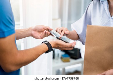 Deliveryman Delivering Package Food Order Customer At Home Signing Signature On Tablet Wearing Face Mask Safety Covid-19 Infection Customer Delivery Service Logistics Ordering Mail Posting Business