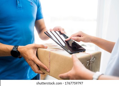 Deliveryman Delivering Package Food Order Customer At Home Signing Signature On Tablet Wearing Face Mask Safety Covid-19 Infection Customer Delivery Service Logistics Ordering Mail Posting Business 