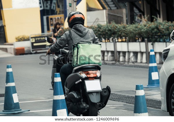 Deliveryman\
driving through the city on a motorbike.\
