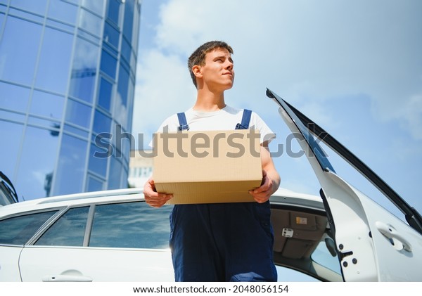 Deliveryman holds
parcels at the car,
delivering