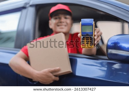 Deliveryman Inside The Car Smiling While Holding Package Box And Showing Edc Machine For Cashless Payment
