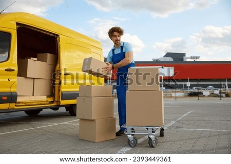Deliveryman stacking parcel boxes into trolley cart providing courier service