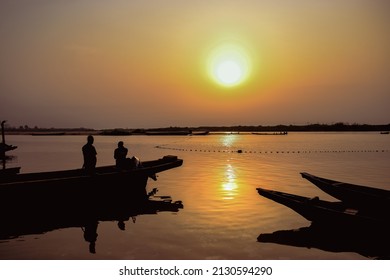 Delta State, Nigeria - December 9, 2021: African Fishermen Setting Out For Fishing Adventure. Fishery Business In Africa.
Fishing Boats By A River Bank. Reflection On A Water Surface.