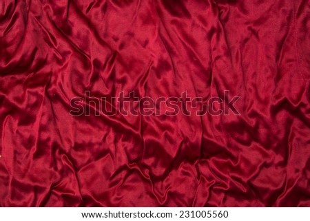 Deluxe crumpled red silk cloth background with waves and drapery. Backdrop for fashion luxury design