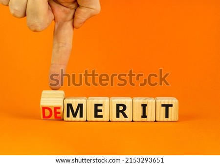 Demerit or merit symbol. Businessman turns wooden cubes and changes the concept word Demerit to Merit. Beautiful orange table orange background. Business and demerit or merit concept. Copy space.