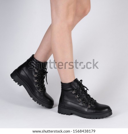 demi seasonal female black leather shoes with lacing on model legs shot in studio on a white background. Beautiful stylish pair of shoes for catalog