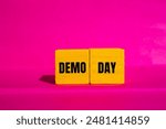 Demo day message written on yellow wooden cubes with pink background. Conceptual demo day symbol. Copy space.