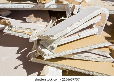 Demolished plasterboard wall, made of plaster and cardboard, with fragments of material and dust in a construction site