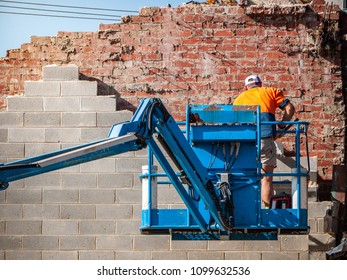 Demolition Builder Working On Lift Platform To Tear Down A Wall.