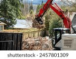 Demolition cleanup and debris removal, heavy equipment with jawbone bucket used to pickup debris and deposit in commercial dumpster for hauling away, residential construction
