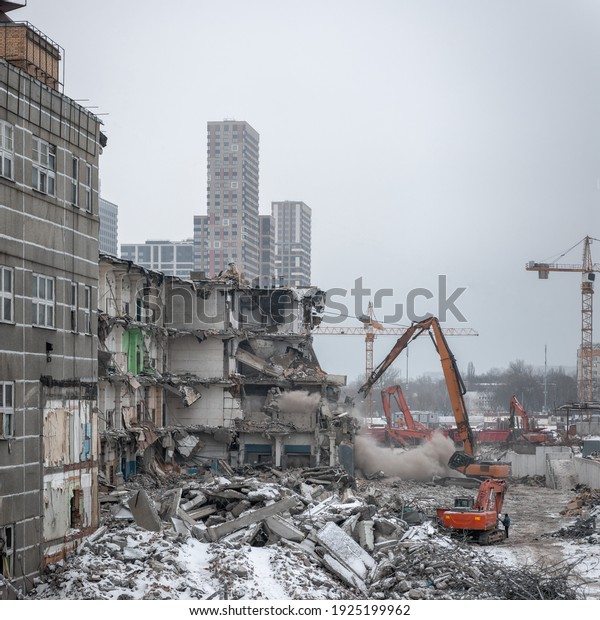 Demolition of an old industrial building in\
Moscow on a overcast winter day with a new high-rise residential\
building in the\
background