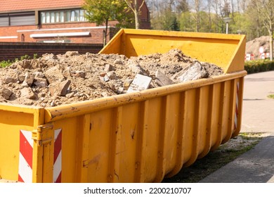 Demolition Waste, Debris From Destruction Or Renovation Of Buildings In A Yellow Container On A Work Site. Concrete And Sand Ready To Be Recycled Into New Building Materials. Circular Economy Concept