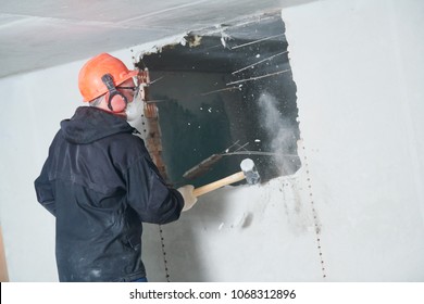 Demolition Work And Rearrangement. Worker With Sledgehammer Destroying Wall