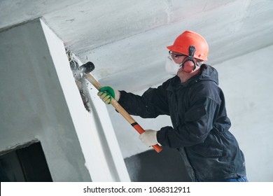 Demolition Work And Rearrangement. Worker With Sledgehammer Destroying Wall