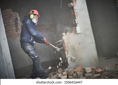 demolition work and rearrangement. worker with sledgehammer destroying wall