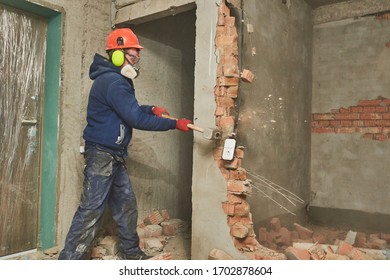 Demolition Work And Rearrangement. Worker With Sledgehammer Destroying Wall