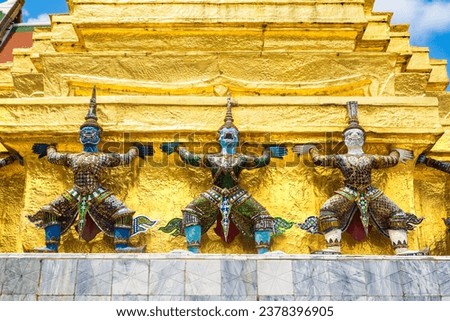 Demon Guardian Statues are supporting golden Chedi stupa at Wat Phra Kaew temple in a sunny day