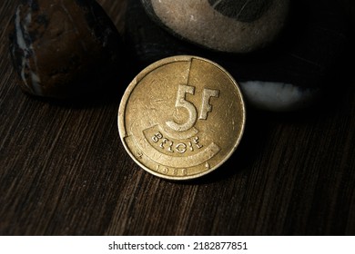 Demonetized Belgian Coin. 5 Francs Reverse 1986 Dutch Text. Brass Coin With Stones On A Dark Background.