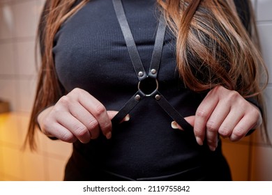 demonstrates a leather accessory on herself. Bright leather garment detail. Stylish belts on clothes. Leather harness.