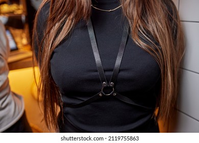 demonstrates a leather accessory on herself. Bright leather garment detail. Stylish belts on clothes. Leather harness.