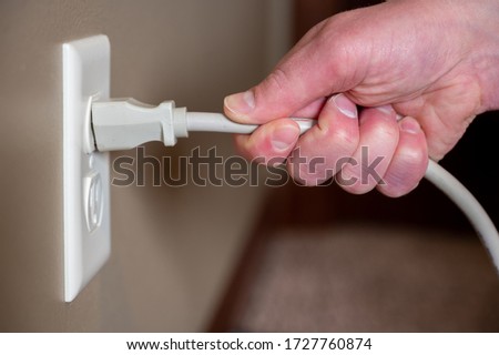 Demonstrating incorrect method of pulling power cord from electrical outlet