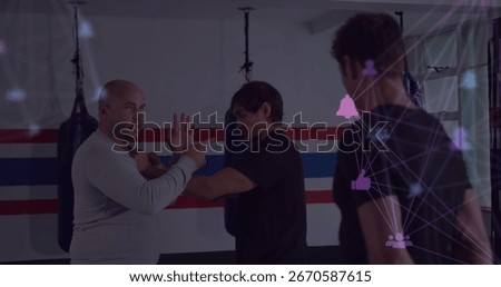 Demonstrating instructor guiding student through wrist control move in gym, with network overlay. Martialarts, combattraining, functionalfitness, dynamic, athletic, strength, discipline