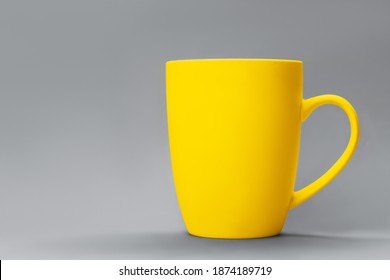 Demonstrating trendy colors 2021 - Gray and Yellow. Yellow cup of cofee against grey background. Minimal concept. Copy space, muck up, front view. - Shutterstock ID 1874189719