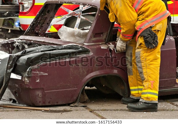 Demonstration of rescue work. Firefighters\
break into a car after an accident. Rescue team retrieve the victim\
from the burned car. Training\
firefighters.