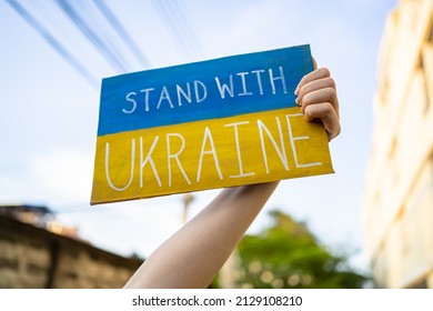 Demonstrator holding "Stand with Ukraine" placard - Shutterstock ID 2129108210
