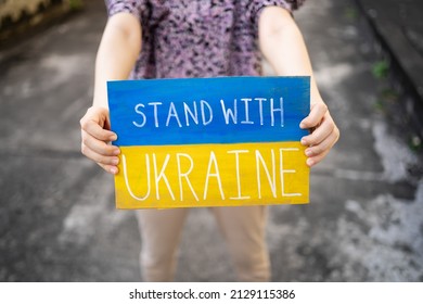 Demonstrator holding "Stand with Ukraine" placard - Shutterstock ID 2129115386