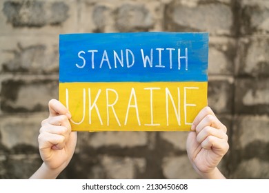 Demonstrator holding "Stand with Ukraine" placard - Shutterstock ID 2130450608