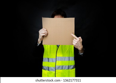 Demonstrators In Yellow Vests On A Black Background With A Cardboard Blank Sign, The Protest Of The Population In France Against The Increase In The Cost Of Fuel, Excessive Living Expenses And High