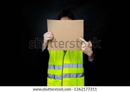 Demonstrators in yellow vests on a black background with a cardboard blank sign, the protest of the population in France against the increase in the cost of fuel, excessive living expenses and high