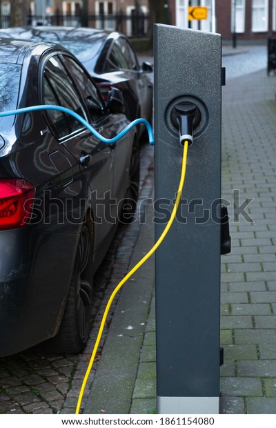 Den Bosch,
Netherlands - 11.24.2020: Electric eco car charging station plug in
to a hybrid car on the street. Car charger on the street in
Netherlands - part of dutch
infrastructure.