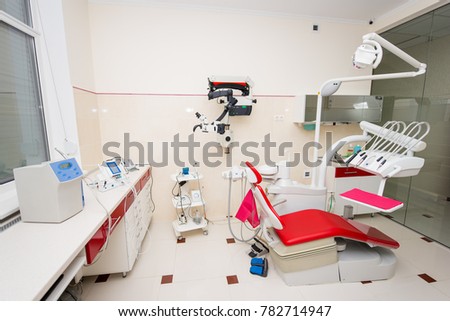 Denatal chair and modern dental equipment in red and white dental clinic room