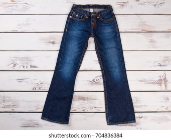 Denim Bell Bottom Trousers. Dark Women Jeans On White Wooden Background, Top View.