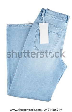 Denim blue jean, folded blue jeans pants isolated on white background, top view. Back side of jeans with pocket and blank label tag with copy space, mockup, template.
