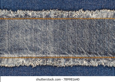 Denim blue jeans fabric frame. Bleached denim fabric with fringe edge and straight stitch with orange thread, on blue denim background, text place, copy space. Worn Jeans Casual Double Color patch