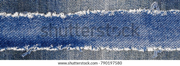 Denim frame.\
Ripped denim fabric with fringe edge on bleached denim background,\
text place, copy space. Worn Jeans Casual Double Color patch.\
Classic blue denim pattern texture\

