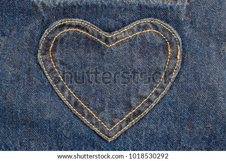 denim heart frame on denim jeans background.  denim heart patch with straight stitch with orange thread, on blue jeans background, text place, copy space. 