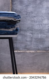 Denim jeans at shelf or stool. Stack of jeans near abstract background texture surface