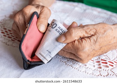 Denmark money. An elderly woman takes out 50 Danish kroner notes from her wallet. Financial concept. Pensions in Denmark