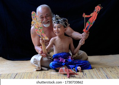 Denpasar, Bali Province, Indonesia, 5 December 2013: A Grandfather In Bali Is Teaching A Grandson To Play Traditional Balinese Shadow Puppets.