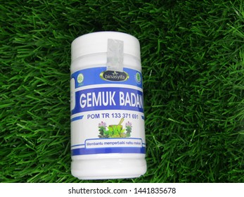 Denpasar, Indonesia - July 4 2019 : Close up view of gemuk badan capsules for fatter body,  isolated on green grass background ready for sale. Good for daily consume 