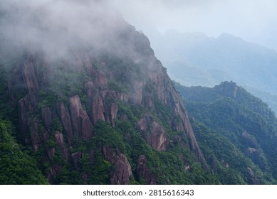Dense clouds and mist surround the steep granite peaks of Sanqingshan Mountain located in the Jiangxi province of China during a summer day