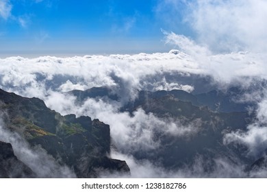Dense clouds over mountains range on sunny day. View from Pico do Arieiro on Portuguese island of Madeira
