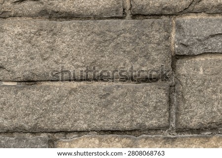 Dense masonry backdrop featuring rectangular hand-split ashlar blocks of natural stone. Deep crystalline texture variations and heavy chiseled lines create a strong, solid historical theme.