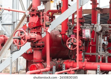 A dense network of red pipes, valves, and gauges part of a fire suppression or industrial fluid transfer system, in an outdoor setting.