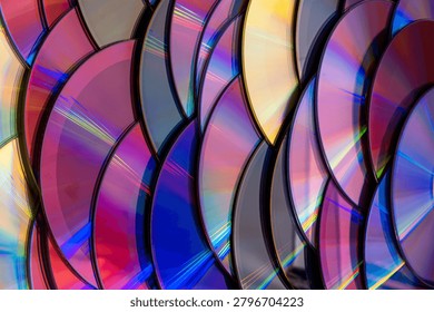 a dense, overlapping pattern of compact discs with rainbow light reflection arranged like fish scales